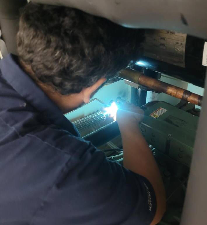 Technician Repairing an Environmental Test Chamber A skilled technician performing maintenance on an environmental test chamber, focusing on a component inside the machine with welding equipment.